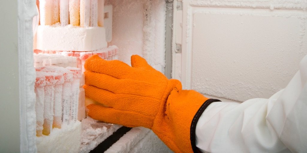 Researcher's arm retrieving medical samples from freezer.